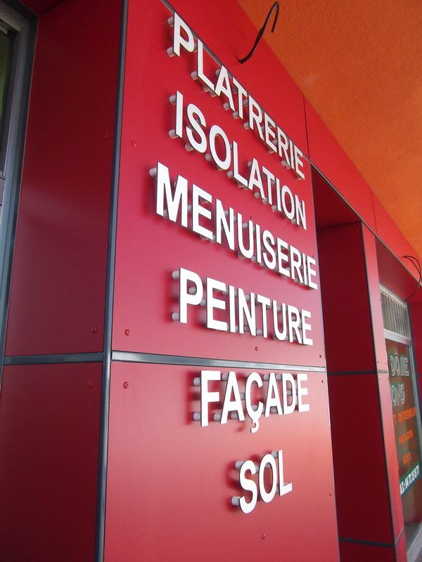 Lettres découpées en relief posées sur une façade rouge