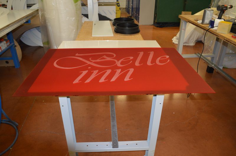 Logo découpé en plastique sur un panneau rouge à l'atelier
